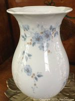 Front view of white porcelain vase with subtle blue floral decoration, showing vase shape and details