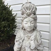 Front close-up of the Kwan Yin statue showing facial features, headdress, and hand gesture