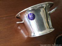Side view of the silver plated planter showing the indigo blue medallion with silver monogram and one handle