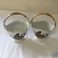 Top view of the pair of porcelain baskets showing the gilded handles and scalloped rim detailing.