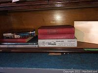 Shelf with seven hardcover books and one box including the Oshawa and Whitby City Directory and Statutes of Ontario 1926