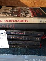 Six books stacked; mainly spines visible showing four volumes of 'Doctors of Death' and 'Let's Kill Uncle' hardcover books along with the softcover 'The Long Generation'.