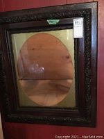 Front view of the ornate wooden picture frame with oval glass opening and measurement sticker visible.