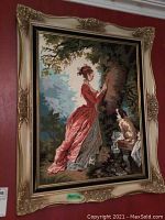 Photo of complete needlepoint artwork in an ornate gold-tone wooden frame on a red wall.