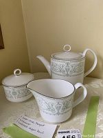 Photo showing the full teapot, creamer, sugar bowl with lid, and handwritten note describing the items