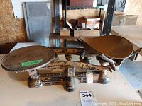 Full view of the vintage mechanical balance scale showing the two pans and the balance beam with worn paint.