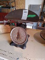 Front-angle view of the vintage mechanical weigh scale showing the rusted dial, needle, and metal weighing platform.