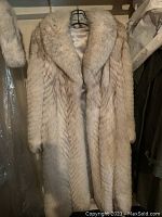 Full front view of the silver fox fur coat on hanger showing texture, length, and lining.