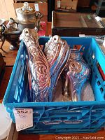 Set of four chromed stove legs and one decorative detailing piece in blue crate.