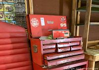 Red Herland metal tool chest upper half with stickers and multiple drawers containing tools