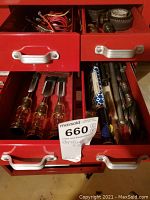 Open red metal drawers showing assorted hand tools: screwdrivers, chisels, punches, and electrical wires.