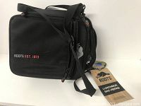 Photo of black Roots lunch bag front view with 'ROOTS EST. 1973' logo embroidered