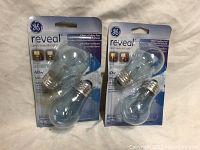 Two packages of GE Reveal 40 watt light bulbs, each package contains two bulbs.