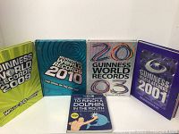 Front covers of four Guinness World Records books (2003, 2009, 2010, 2011) along with the humorous guide book by The Oatmeal.