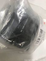 Close-up of one matte black knob in its original plastic bag, showing finish and partial label details.