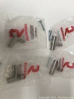 Four metal knobs in original Richelieu packaging, each with the included screws visible.