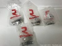 Four Richelieu brand cabinet knobs in their original clear plastic packaging with red Richelieu logo.