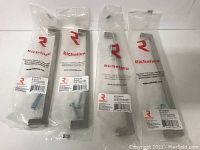Four new metal cabinet pulls still in original plastic packaging, brushed nickel finish, each includes screws, Richelieu Hardware brand visible on packaging.
