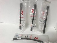 Four metal cabinet pulls in original packaging showing the brushed oil-rubbed bronze finish and rectangular bar design.