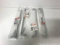 Set of four Richelieu chrome metal cabinet pulls in original sealed plastic packaging on white background.