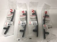 Four Richelieu branded matte black metal cabinet pulls still sealed individually in original plastic packaging.