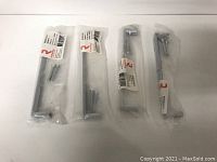 Set of four matte chrome metal pulls in original packaging with screws visible, laid out flat on white surface