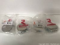 Four Richelieu branded polished nickel cabinet pulls in clear plastic packaging, arranged side by side.