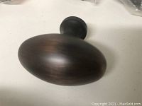 Close-up photo of one oval traditional metal knob showing brushed oil-rubbed bronze finish with smooth surface.