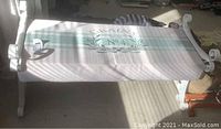 Full view of refurbished metal framed bench with printed fabric seat and decorative scroll metal arms.