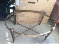 Angled view of metal coffee table base with boxed glass top behind