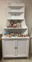Full view of the white corner hutch loaded with decorative items (not included).