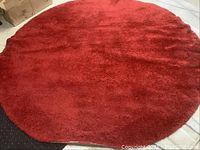 Full view of a round red carpet laid on floor, showing size and color