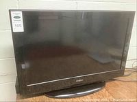Full front view of the black Insignia 32 inch TV on its base showing the screen and frame.