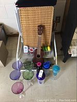 Full lot shot showing picnic basket, ukulele, various plastic glasses, travel cups, and lawn chairs