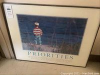 Framed motivational poster titled 'Priorities' showing a child in a red and white striped shirt and jeans, standing on grassy area looking out at water.