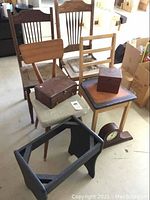Full view of the lot showing three different wooden chairs, one black wooden stool frame, two wooden jewel boxes on chairs, and the mantel clock on the floor.