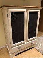 Front view of the wardrobe showing two chalkboard painted doors with floral motifs and bottom drawer with handles