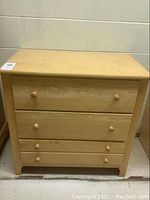 Front view of the 3 drawer dresser made of light-colored wood, showing the drawer layout and condition.