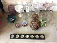 Overview of all glass and crystal items grouped together on the floor, showing various vases, candle holders, and paperweights.