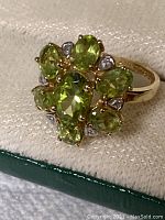Top perspective of ring inside box showing cluster of seven peridot stones and six diamond accents