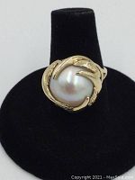 Front view of ring on black display stand showing pearl and gold setting