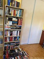 Full bookshelf with multiple shelves of books and boxes on the floor