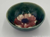Top view of ceramic bowl showing large Anemone flower pattern in shades of pink and maroon against teal-green background interior.