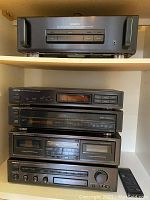 Five Onkyo audio components stacked on white shelf