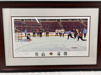 Framed limited edition art print depicting hockey players on the ice rink practicing shots with goalie, seated in arena stands in background.
