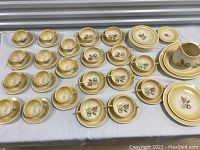 Full lot overview showing cups, saucers, plates, and jug with floral yellow gradient pattern.