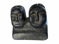 Front view showing two carved heads on block base