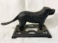 Side profile of black cast iron dog-shaped nutcracker on a rectangular cut-out base.