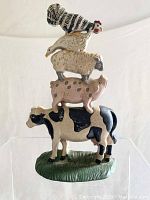 Front view of cast iron stacked farm animals doorstop showing detailed color and painting on cow, pig, sheep, goose, and rooster.