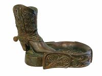 Side view of the cowboy boot styled bronzed metal cigar holder with floral detailing and the horseshoe-shaped ashtray base.